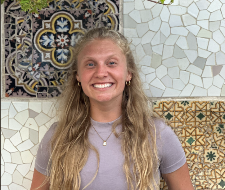 Nikki, founder of Nikki's Kitchen, smiling in front of a colorful mosaic tile wall